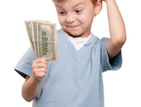 Portrait of a surprised little boy holding a dollars over white background