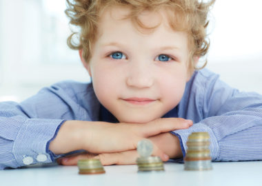 The concept of children's economic education. Young boy build a tower by coins.