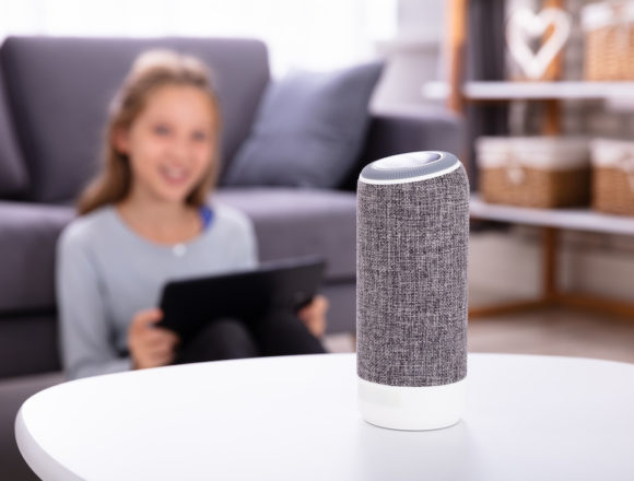 Close-up Of A Wireless Speaker On Furniture With Girl In Background