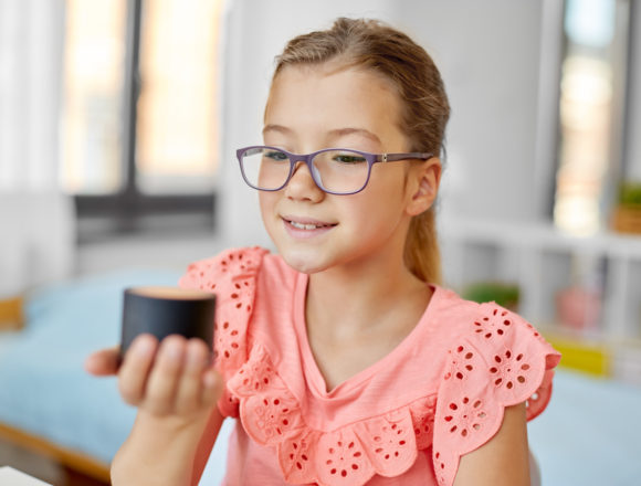 children, education and technology concept - student girl using smart speaker at home